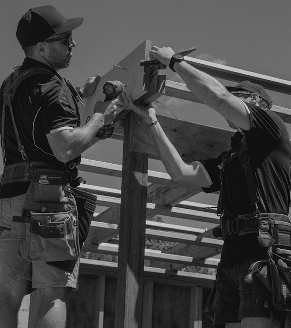 Two carpenters fixing a roof truss on a residential frame.