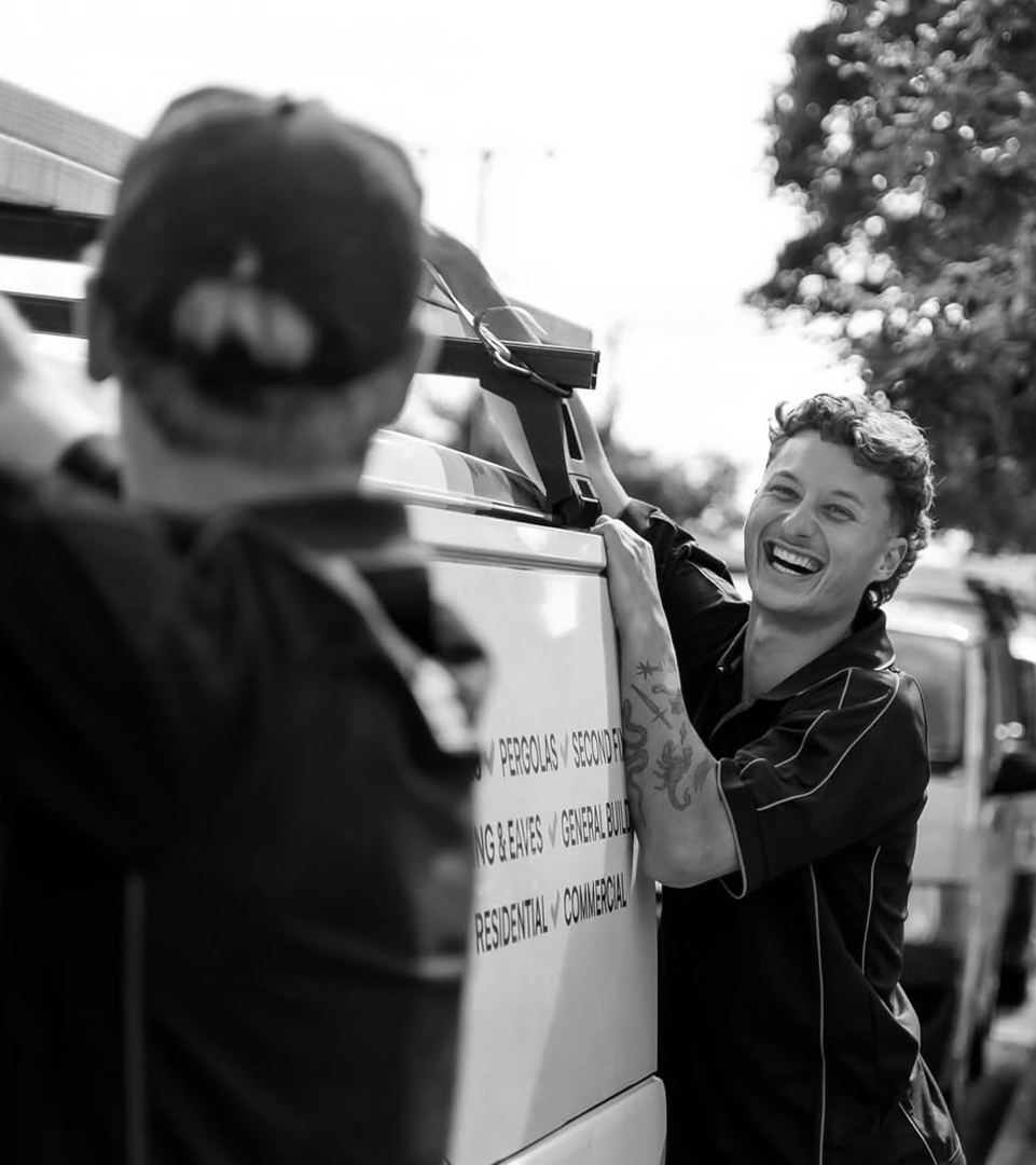 Two tradies loading gear onto a work ute, laughing.